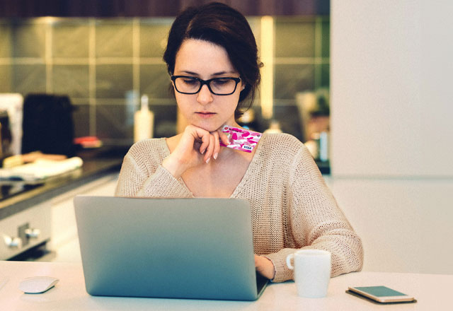 Woman holding credit card looking at laptop.