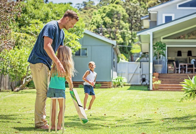 Family in back yard playing cricket