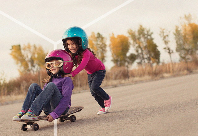 Young girls playing on a skateboard.